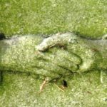 CLASPED HANDS: symbolizes the deceased being led into Heaven by a husband, wife or family member. Look for cufflinks (male) and ruffles (female). The hand with the palm facing outward is considered to be the helper, the other is considered to be the deceased.