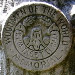 WOODMEN OF THE WORLD: symbols include trees, tree stumps, log piles, the legend cum tacit, clamat (though silent, he speaks).